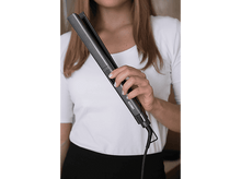 Charger l&#39;image dans la galerie, Une femme en chemise blanche tient un lisseur gris, les mains sont visibles.
