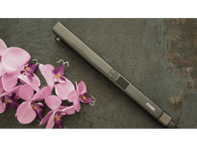 Charger l&#39;image dans la galerie, Fer à lisser gris à côté d&#39;orchidées roses sur une surface sombre et texturée.
