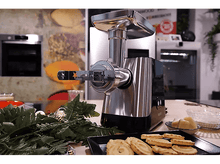 Charger l&#39;image dans la galerie, Scène de cuisine avec un hachoir. Des biscuits, une fougère et un bol d&#39;ingrédients sont sur la table.
