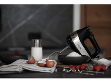 Charger l&#39;image dans la galerie, Mixeur plongeant noir et argent, ingrédients autour: farine, œufs, lait, fraises, dans la cuisine.
