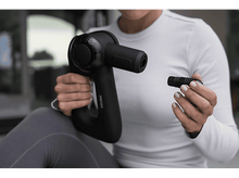 Charger l&#39;image dans la galerie, Une personne tenant un pistolet de massage noir, fixant une tête. Fond blanc.
