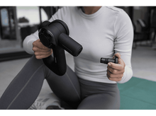 Charger l&#39;image dans la galerie, Une femme assise tenant un appareil de massage noir et un accessoire.
