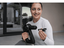 Charger l&#39;image dans la galerie, Femme tenant un pistolet de massage noir et un accessoire, souriant à la caméra.
