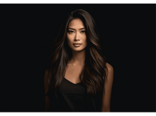 Charger l&#39;image dans la galerie, Une femme aux cheveux foncés et un haut noir pose sur un fond noir.
