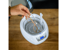 Charger l'image dans la galerie, Une main place des lunettes dans un nettoyeur à ultrasons Koenic blanc.
