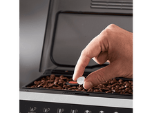 Charger l&#39;image dans la galerie, Une main tenant un petit comprimé. Le comprimé est placé à l&#39;intérieur d&#39;une machine à café.
