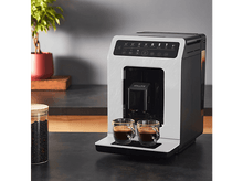 Charger l&#39;image dans la galerie, Une machine à café avec deux tasses d&#39;espresso sur un comptoir, avec des grains et une plante.
