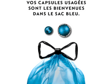 Charger l&#39;image dans la galerie, Sac poubelle bleu avec deux capsules Nespresso usagées sur fond blanc.
