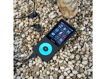 Charger l&#39;image dans la galerie, Lecteur MP3 noir et gris sur des petits cailloux, écouteurs noirs à proximité.
