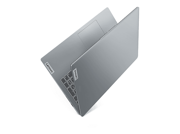 Un ordinateur portable Lenovo argenté, partiellement ouvert, sur fond blanc. Le clavier est visible, avec le logo Lenovo dans le coin.