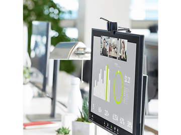 Un moniteur d'ordinateur affiche un appel vidéo avec plusieurs participants, des graphiques et des tableaux.