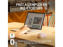 Charger l'image dans la galerie, Une femme utilise un ordinateur portable. Une souris sans fil est à côté de l'ordinateur portable sur une table en bois.
