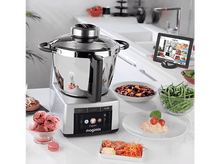 Charger l&#39;image dans la galerie, Une scène de cuisine avec un robot culinaire, de la nourriture et une tablette.
