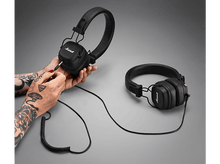 Charger l&#39;image dans la galerie, Casque noir avec logo Marshall, branché à une main tatouée.
