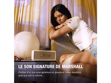 Charger l&#39;image dans la galerie, Une femme assise sur un canapé, avec un haut-parleur et un modèle de voiture sur la table.
