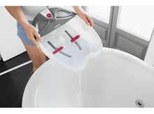 Charger l&#39;image dans la galerie, Une personne verse de l&#39;eau d&#39;un bain de pieds dans une baignoire.
