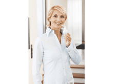 Charger l&#39;image dans la galerie, Femme blonde souriante, tenant un inhalateur. Elle porte une chemise bleu clair, à l&#39;intérieur.
