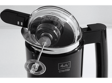 Charger l&#39;image dans la galerie, Un mousseur à lait noir avec un couvercle transparent, avec un fouet en métal à l&#39;intérieur, en gros plan sur du blanc.
