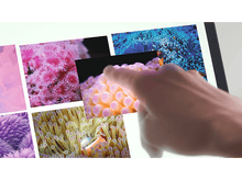 Charger l&#39;image dans la galerie, La main d&#39;une personne touche une image sur une tablette. D&#39;autres images sont en arrière-plan.
