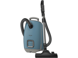 Aspirateur Miele bleu avec des accents argentés, un tuyau et une brosse. Fond noir.
