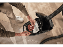 Charger l&#39;image dans la galerie, Une personne retirant un filtre d&#39;un aspirateur noir, montrant les composants internes.
