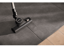 Charger l&#39;image dans la galerie, Une tête d&#39;aspirateur noire sur des carreaux gris foncé et un sol en bois.
