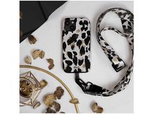 Charger l'image dans la galerie, Coque de téléphone à motif léopard, reliée à un cordon assorti, sur une surface blanche.
