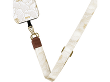 Charger l'image dans la galerie, Coque de téléphone crème avec imprimé floral, reliée à une sangle crème avec accessoires dorés.
