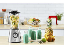 Charger l&#39;image dans la galerie, Mixeur avec des fruits, des bouteilles de jus et un ananas sur une table.
