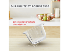 Charger l&#39;image dans la galerie, Bol en verre transparent incliné sur une table en bois, avec un comptoir blanc et un panier de fruits en arrière-plan.
