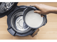 Charger l&#39;image dans la galerie, Une personne verse du liquide d&#39;un pot dans une cocotte-minute noire.
