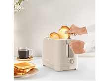 Charger l&#39;image dans la galerie, Un grille-pain avec du pain grillé en train d&#39;être retiré. Une tasse de café et du pain grillé avec de la confiture sont à proximité.
