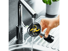 Charger l&#39;image dans la galerie, Main rinçant une lame de mixeur noire sous l&#39;eau courante dans un évier.
