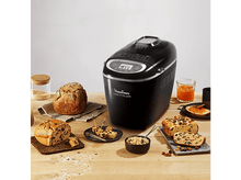 Charger l&#39;image dans la galerie, Une machine à pain noire avec du pain et des ingrédients sur une table en bois.
