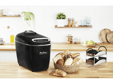 Charger l&#39;image dans la galerie, Une machine à pain noire avec du pain et un panier, sur un comptoir en bois.
