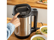 Charger l&#39;image dans la galerie, Une personne appuie sur un bouton d&#39;une machine à soupe argentée et noire.
