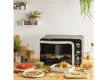 Charger l&#39;image dans la galerie, Un four noir avec de la nourriture sur la table devant lui. Table en bois et mur blanc.
