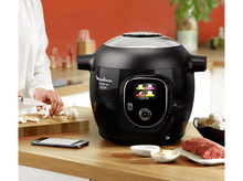 Charger l&#39;image dans la galerie, Personne tranchant des champignons près d&#39;un Moulinex Cookeo noir. Autres ingrédients sur le comptoir.
