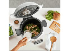 Charger l&#39;image dans la galerie, Un multicuiseur ouvert, avec de la nourriture à l&#39;intérieur et des ingrédients sur le comptoir.
