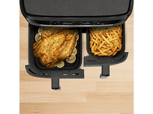 Charger l&#39;image dans la galerie, Une friteuse à air avec un poulet rôti entier et des frites dans des plateaux séparés.
