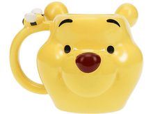Charger l&#39;image dans la galerie, Un mug jaune Winnie l&#39;Ourson avec un visage souriant, des oreilles d&#39;ours et une abeille sur la poignée sur fond blanc.
