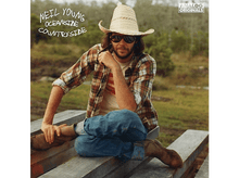Charger l&#39;image dans la galerie, Neil Young, assis sur des planches de bois, portant un chapeau et des lunettes de soleil.
