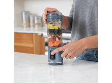 Charger l&#39;image dans la galerie, Une personne utilise un blender Ninja gris rempli d&#39;ingrédients sur un comptoir blanc.
