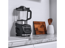 Charger l&#39;image dans la galerie, Blender Ninja noir et argent sur un comptoir en marbre, avec des objets en bois et une planche à découper.
