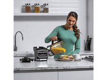 Charger l&#39;image dans la galerie, Femme versant de la soupe d&#39;un blender Ninja dans un bol avec du pain.
