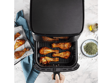 Charger l&#39;image dans la galerie, Friteuse à air avec pilons de poulet cuits. Bouteille d&#39;huile et pot d&#39;épices sur le côté.
