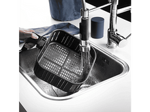 Charger l&#39;image dans la galerie, Un panier de friteuse à air noir est lavé dans un évier en acier inoxydable.
