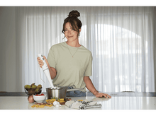 Charger l&#39;image dans la galerie, Une femme dans une cuisine tenant un mixeur plongeant au-dessus d&#39;une casserole sur un comptoir.
