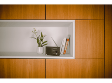 Charger l&#39;image dans la galerie, Une étagère avec une radio, un vase avec des fleurs et deux livres dans un meuble en bois.
