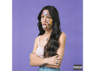 Femme avec des autocollants sur le visage, portant un haut rose, debout devant un fond violet. Le mot 'SOUR'.